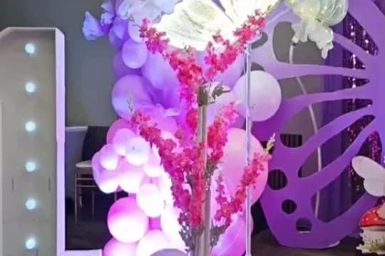 Lavender and white balloon backdrop with a light-up letter and butterfly accents
