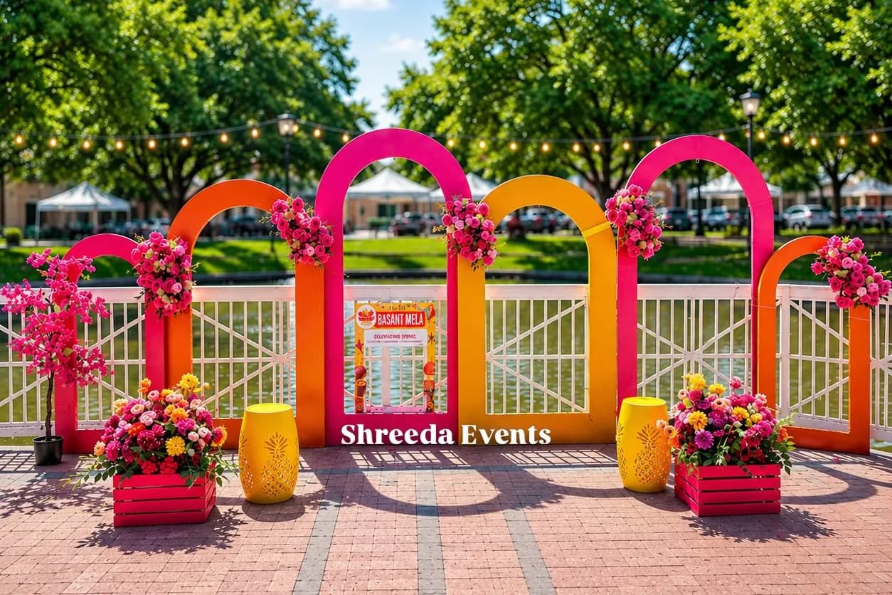 Outdoor entrance of overlapping pink, orange and red arches with flower clusters, planters and yellow stools