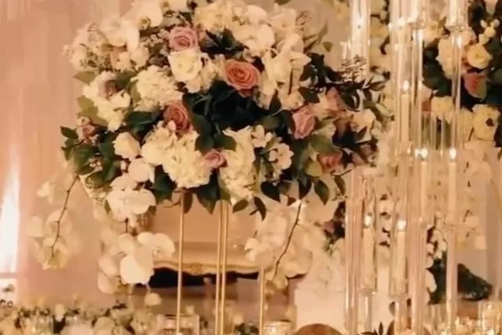 Tall white and blush floral centerpiece on a candlelit dinner table