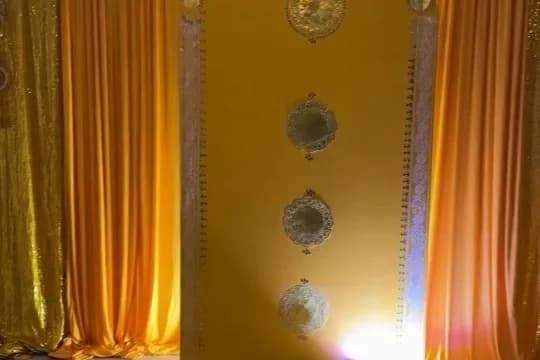 Yellow and gold draped backdrop with soft lights and round mirror accents