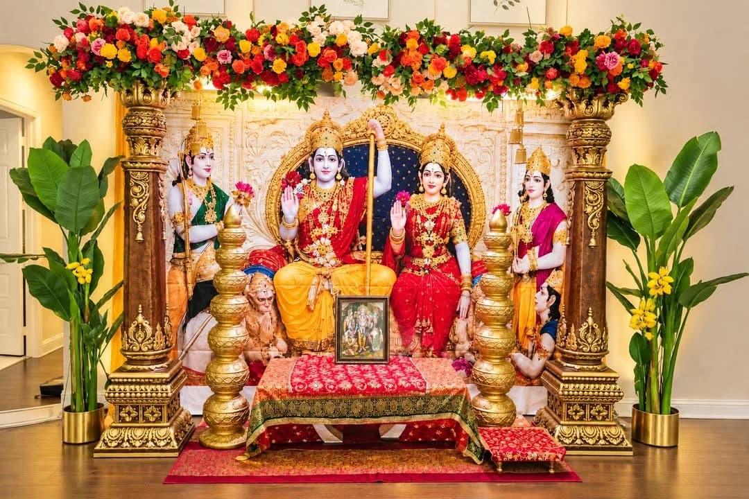 Puja setup with deity murtis on a red and gold platform, framed by marigold and rose garlands