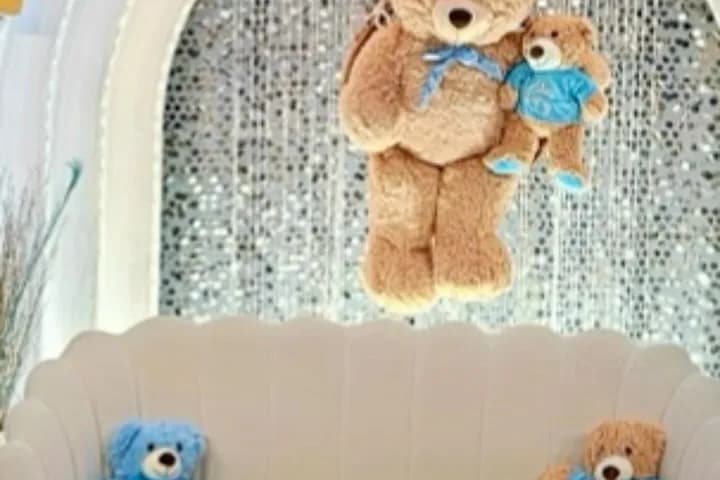 Baby shower backdrop with a shimmer wall, a white sofa and teddy bear decorations