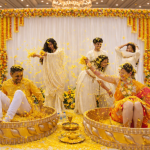 Haldi ceremony decoration with marigold backdrop, white stage draping, brass seating bowls, and floral petals celebration by Shreeda Events in Dallas DFW