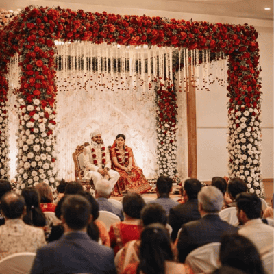 Elegant red and white floral wedding mandap decoration setup with canopy design, ideal for backyard wedding and small to medium wedding hall by Shreeda Events